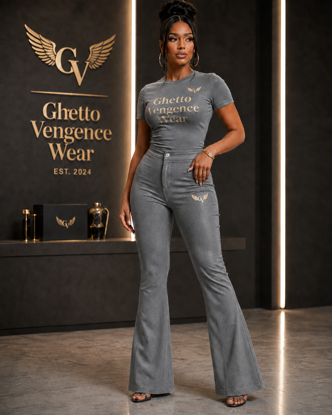 Elevated streetwear meets sophisticated style in the Ghetto Vengence Wear Signature Grey Flare Set. This coordinated women's look features a fitted short-sleeve top paired with high-waisted flare-leg pants for a sleek, flattering silhouette. Rich gold Ghetto Vengence Wear lettering across the chest and signature GV wing logo detailing give the set a polished luxury finish.

Fitted short-sleeve top with gold GV lettering
High-waisted flare-leg pants for a flattering silhouette
Signature GV wing logo detail